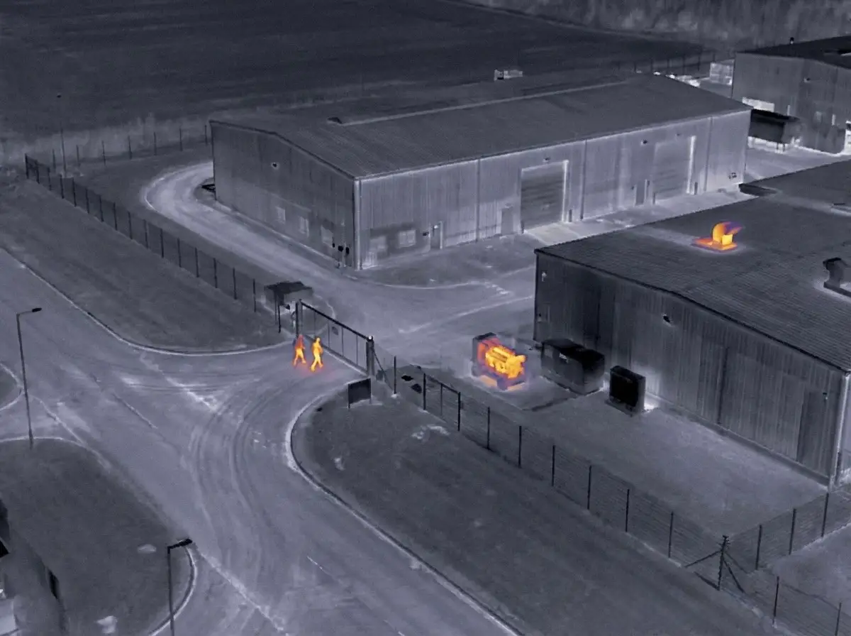 Thermal drone detecting intruders around an industrial site perimeter at night